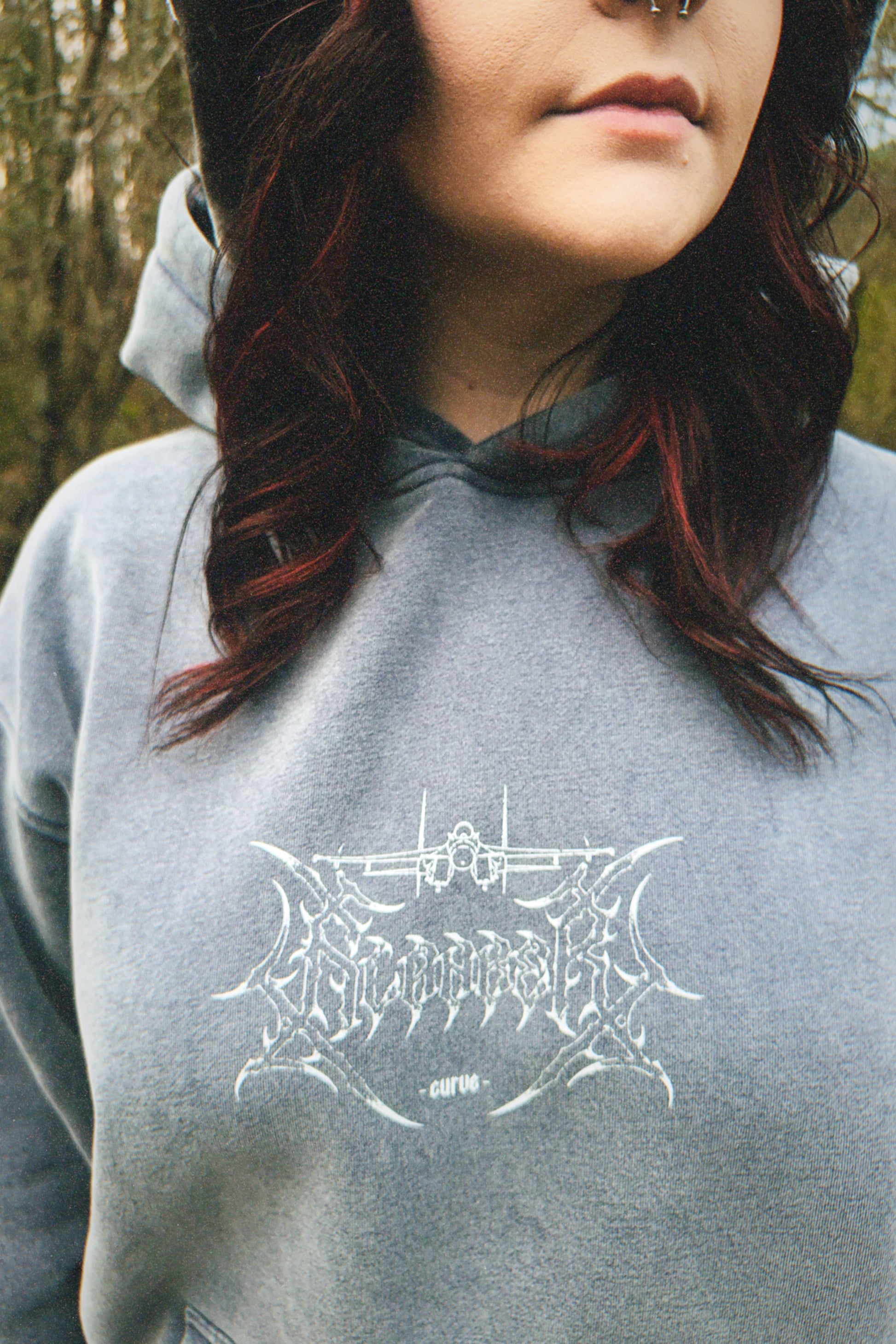 Person wearing grey hoodie with aviation-inspired graphic and streetwear design outdoors