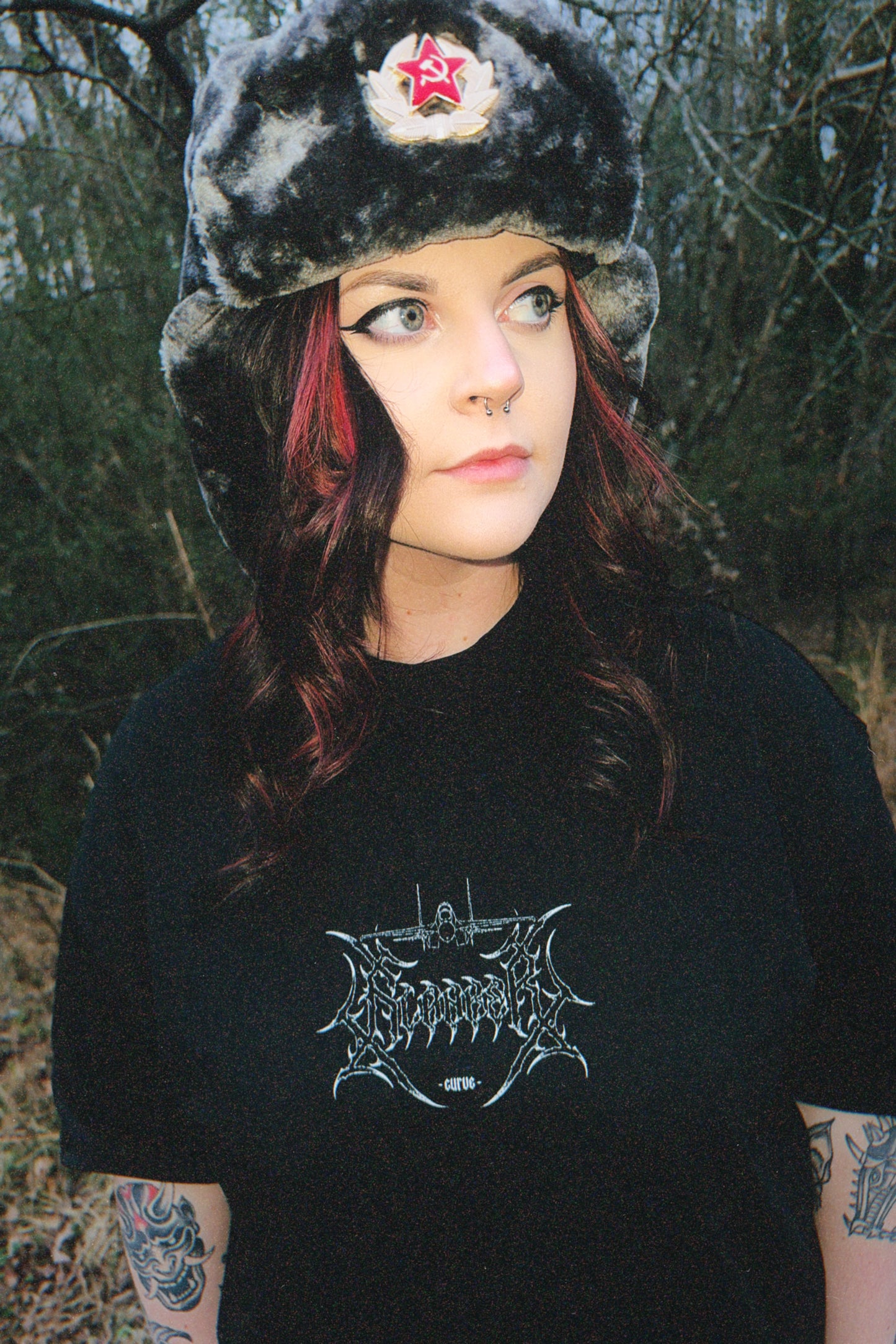Woman outdoors wearing aviation-inspired graphic tee and faux fur hat with red star badge