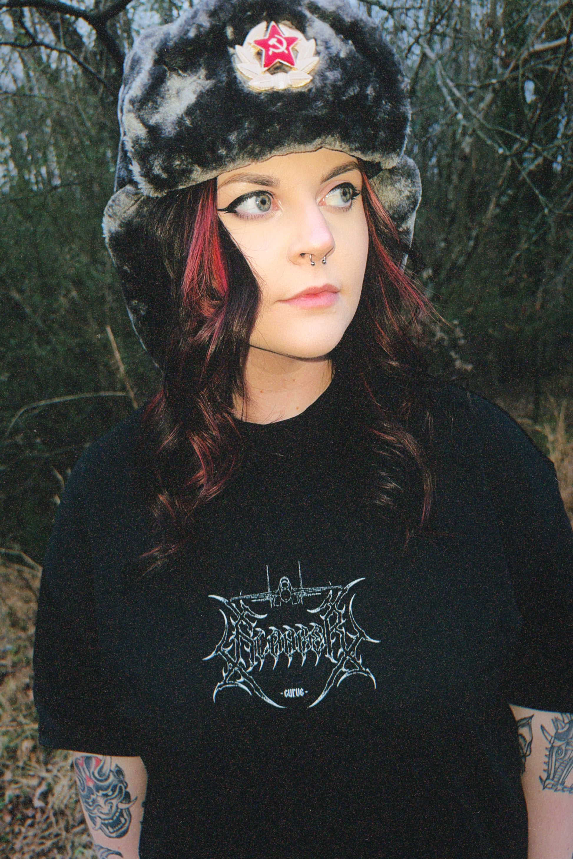 Woman outdoors wearing aviation-inspired graphic tee and faux fur hat with red star badge