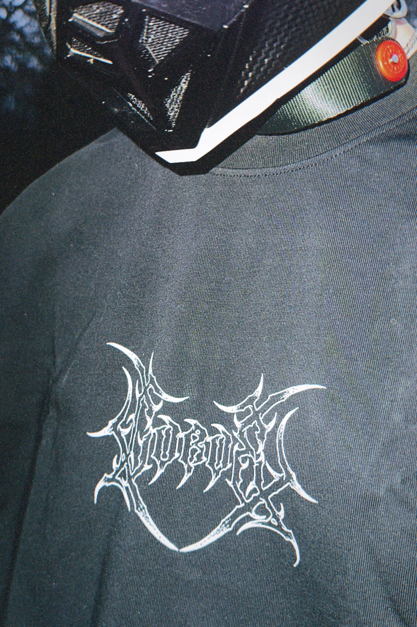 Close-up of black t-shirt with white graphic logo, worn with a modern tactical helmet