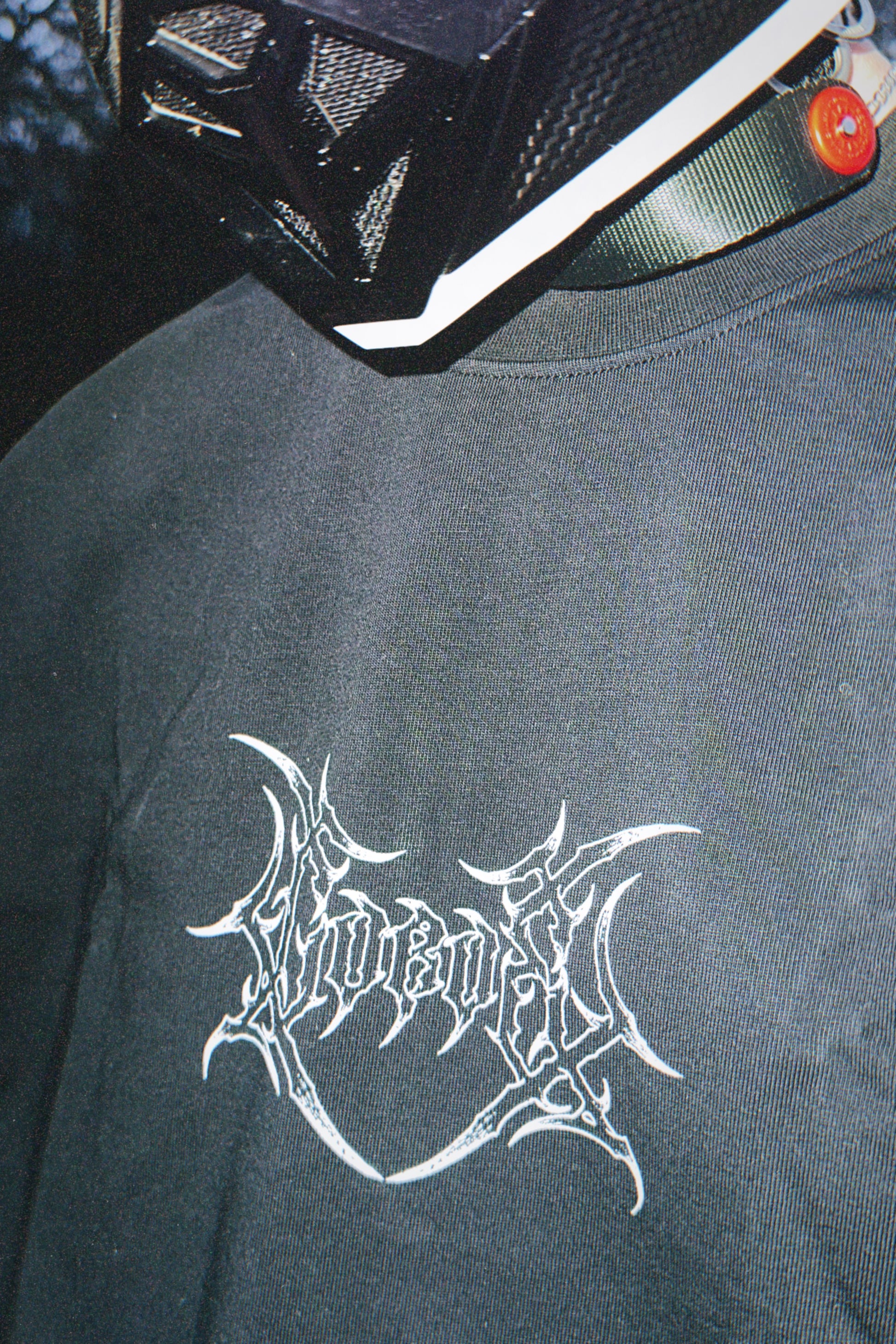 Close-up of black t-shirt with white graphic logo, worn with a modern tactical helmet