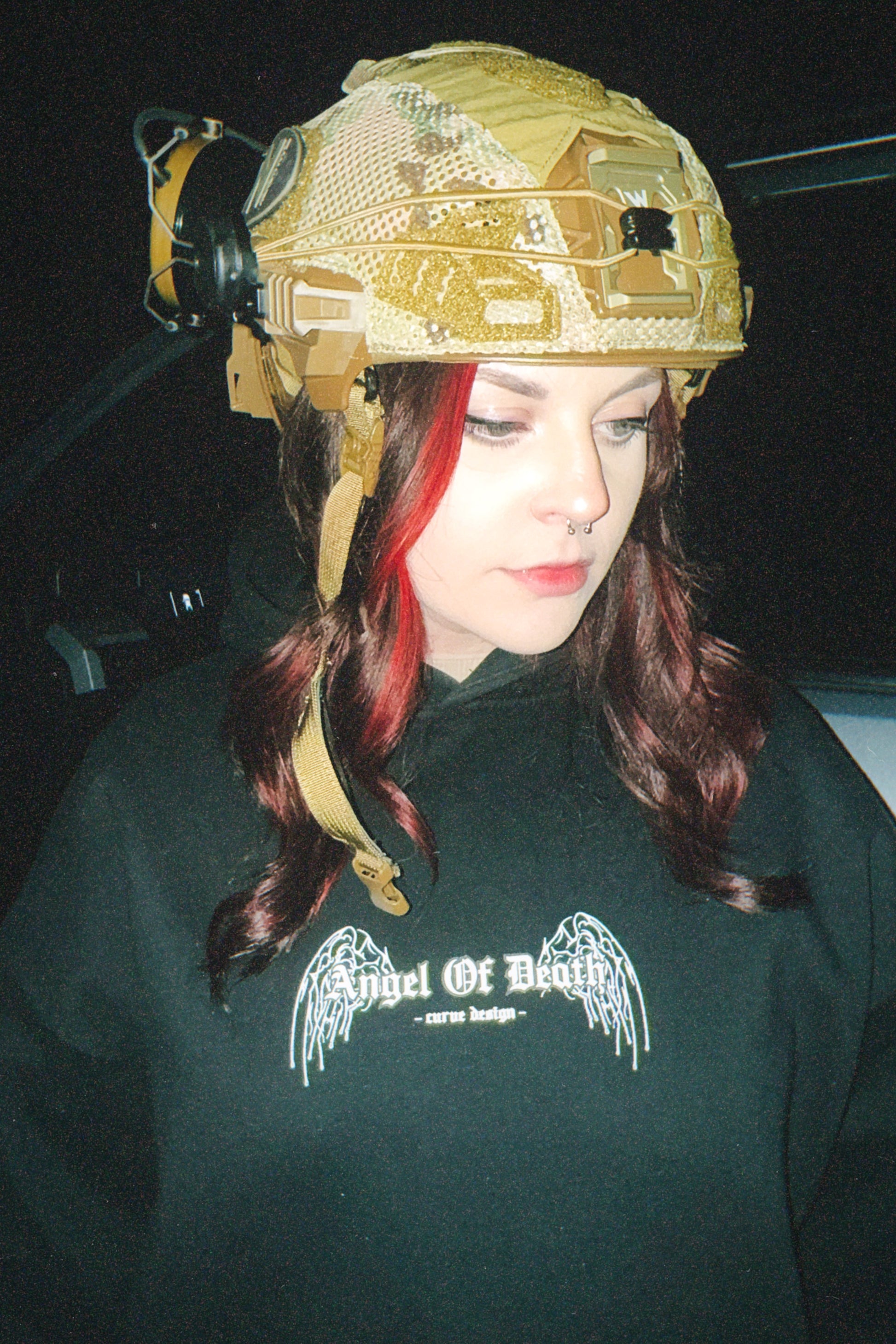 Woman in tactical helmet and black hoodie with Angel Of Death graphic, streetwear style