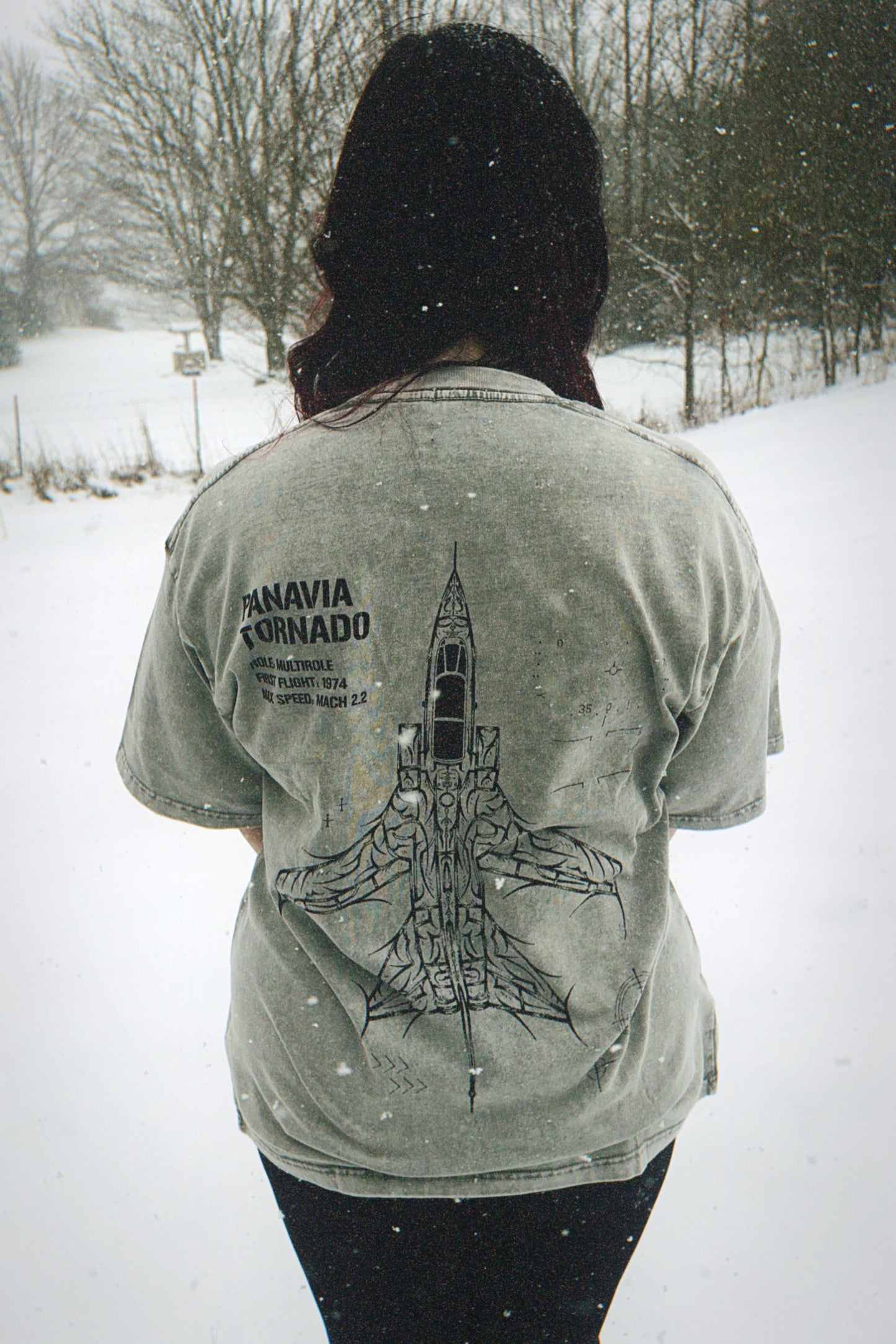 Person in snowy outdoors wearing aviation-inspired t-shirt with Panavia Tornado jet graphic