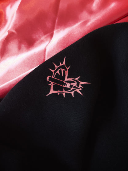 Black streetwear fabric with pink aviation-inspired heart and missile graphic, pink satin background