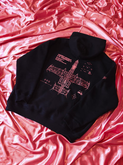 Black hoodie with pink aviation blueprint graphic, displayed on pink satin fabric
