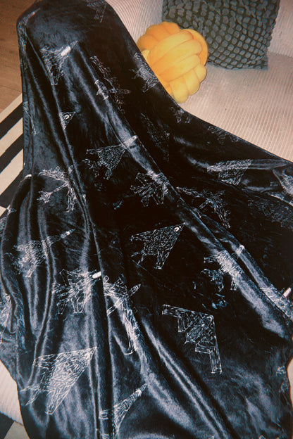 Black aviation-inspired throw blanket with white jet line art on a sofa, modern decor